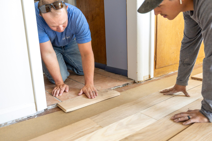 Flooring installers fitting hardwood planks during a residential hardwood floor installation.
