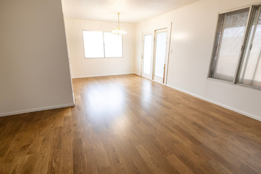 Newly installed hardwood flooring throughout a bright residential living and dining area.