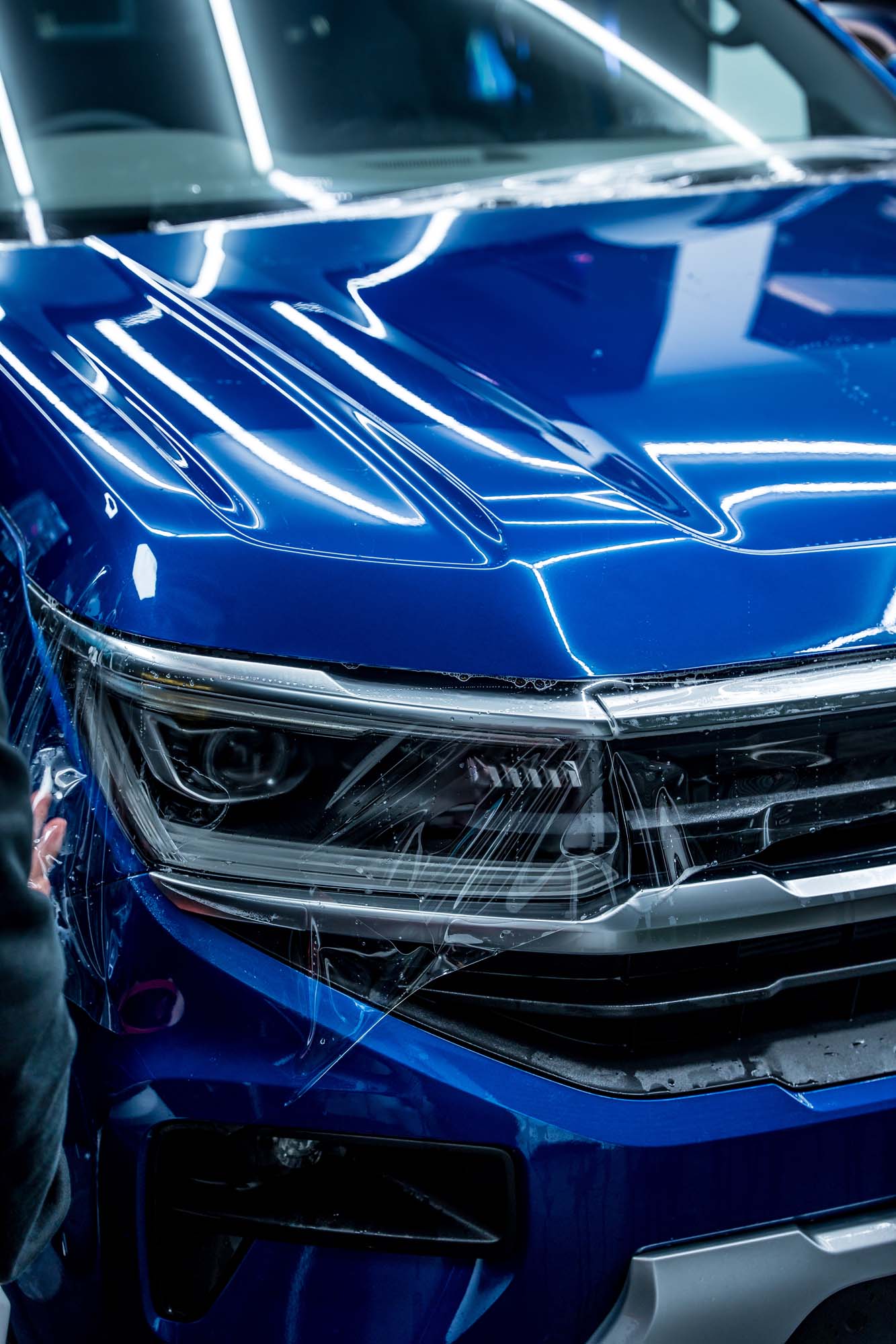 Wax Is Dead X-Gloss PPF finish on a bumper and headlight, live install by Halo Collective