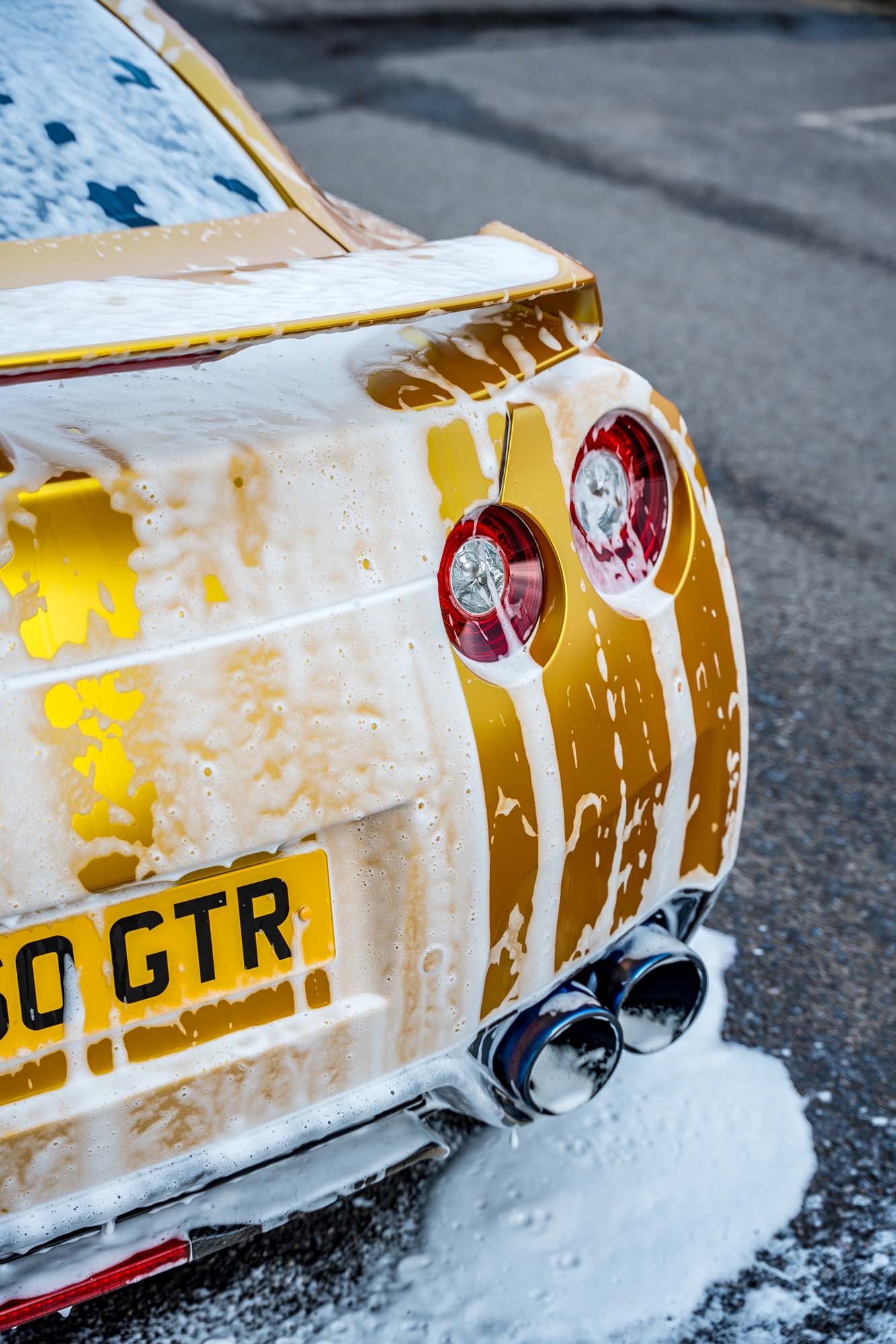 Gold Nissan GT-R fully covered in snow foam during the wash stage, by Halo Collective