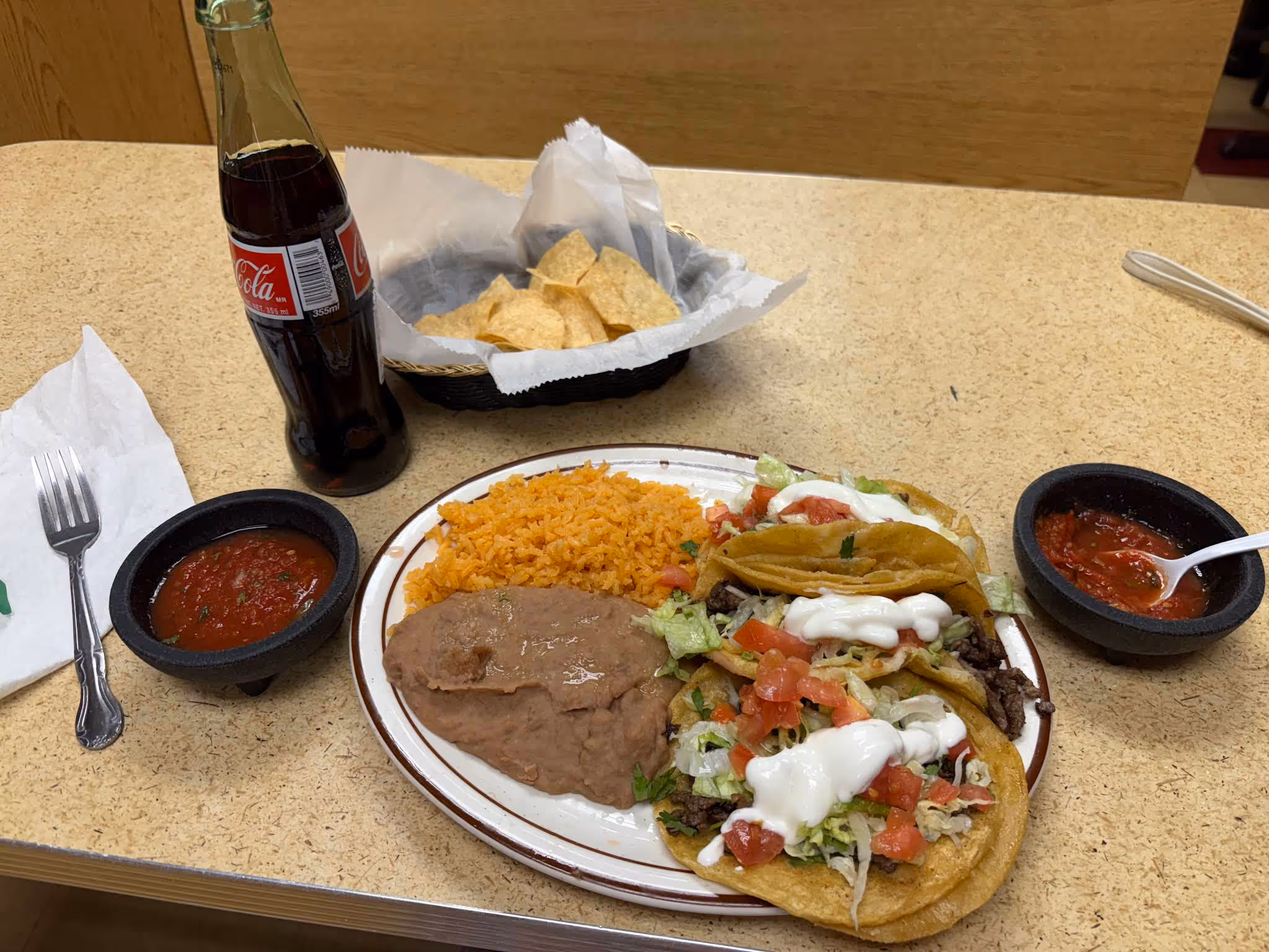 A plate of food with a soda on the table.