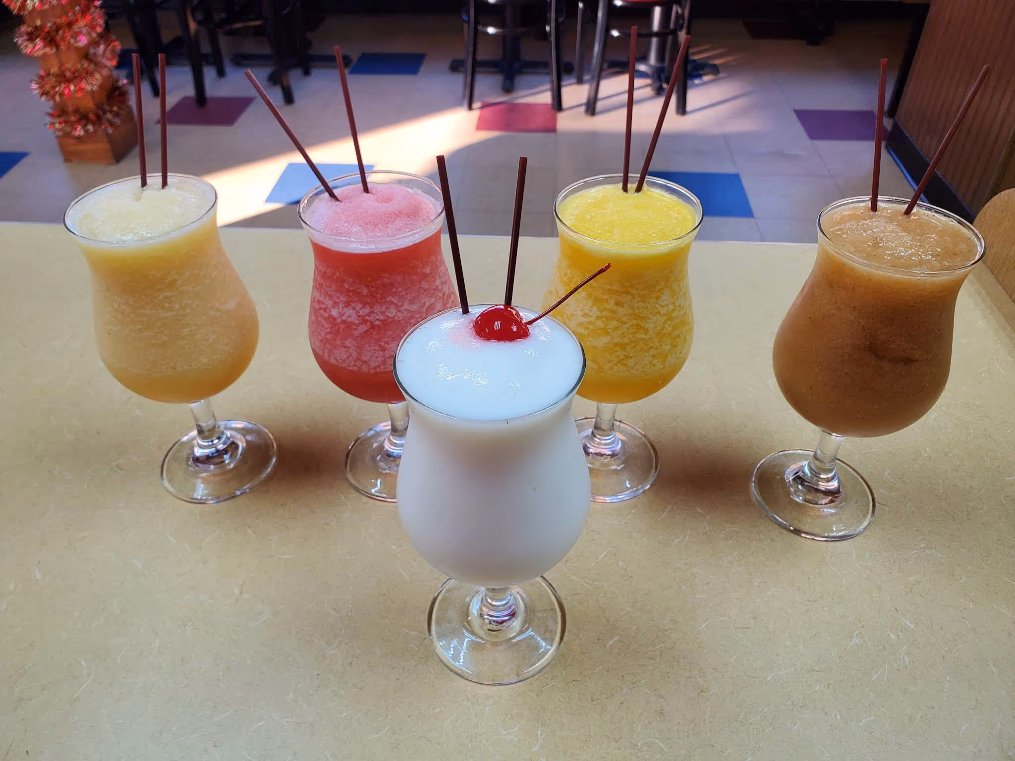 A table with 6 glasses of drinks on it.