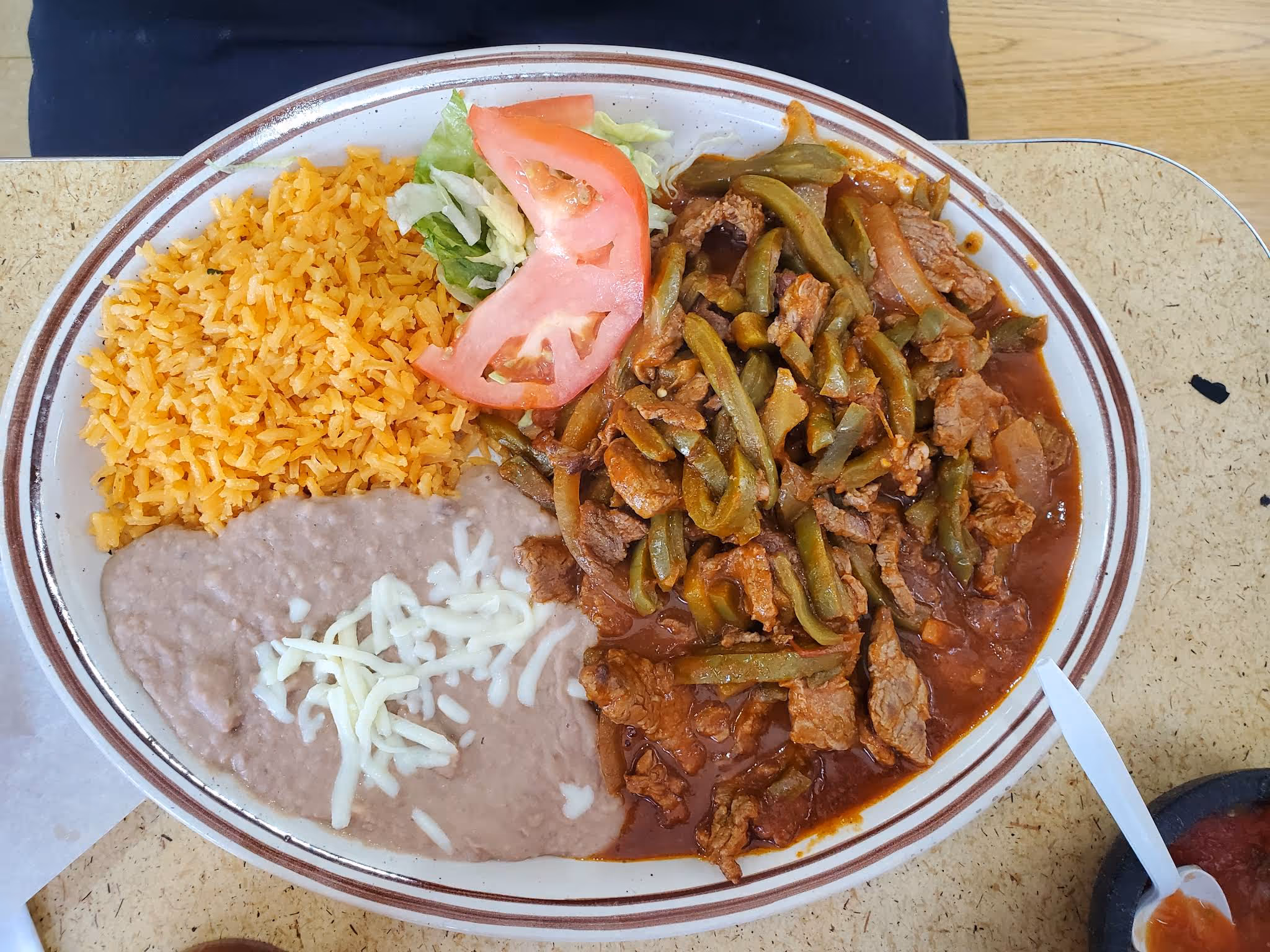 A plate of food with meat, beans, tomatoes, and green beans.