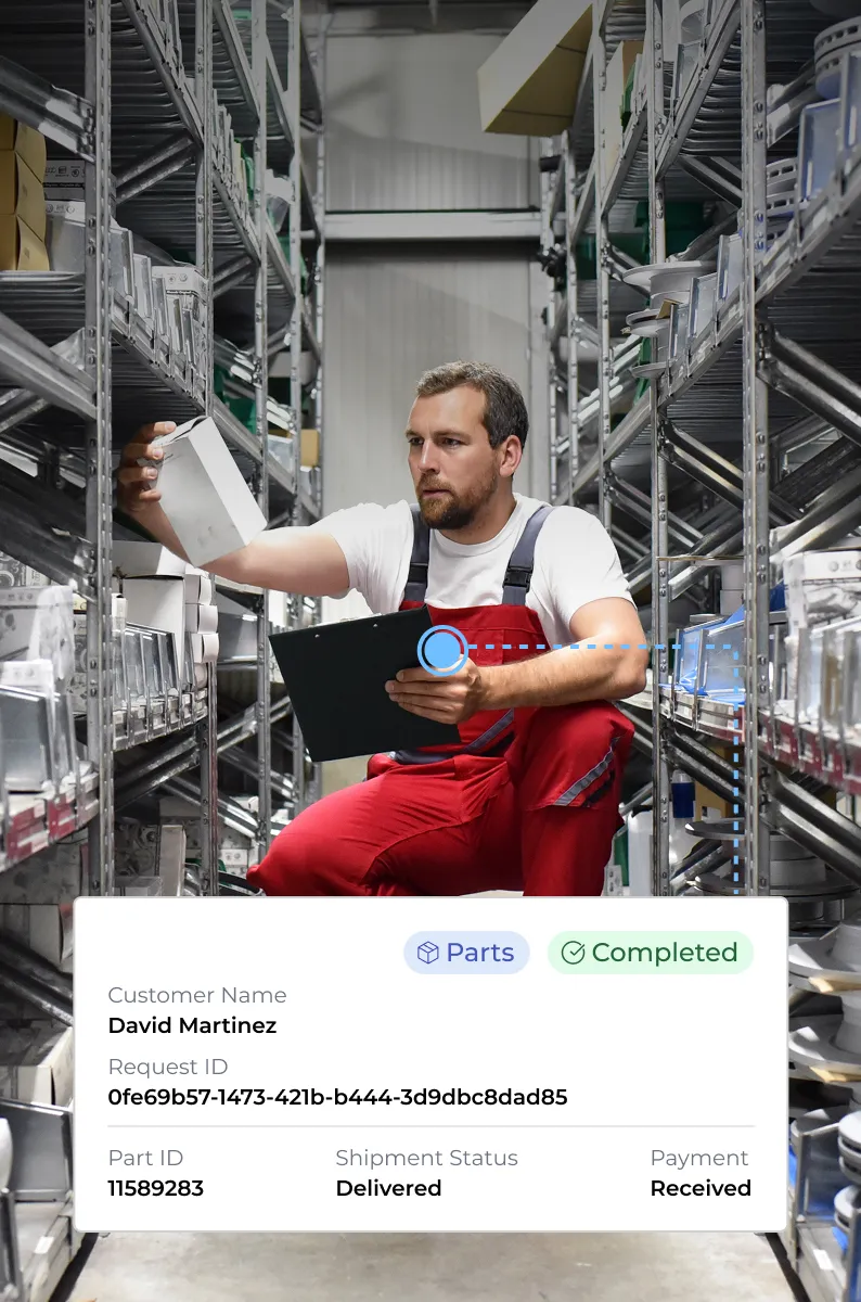 Warehouse worker in red overalls inspecting a box while holding a clipboard between metal shelves filled with packages.