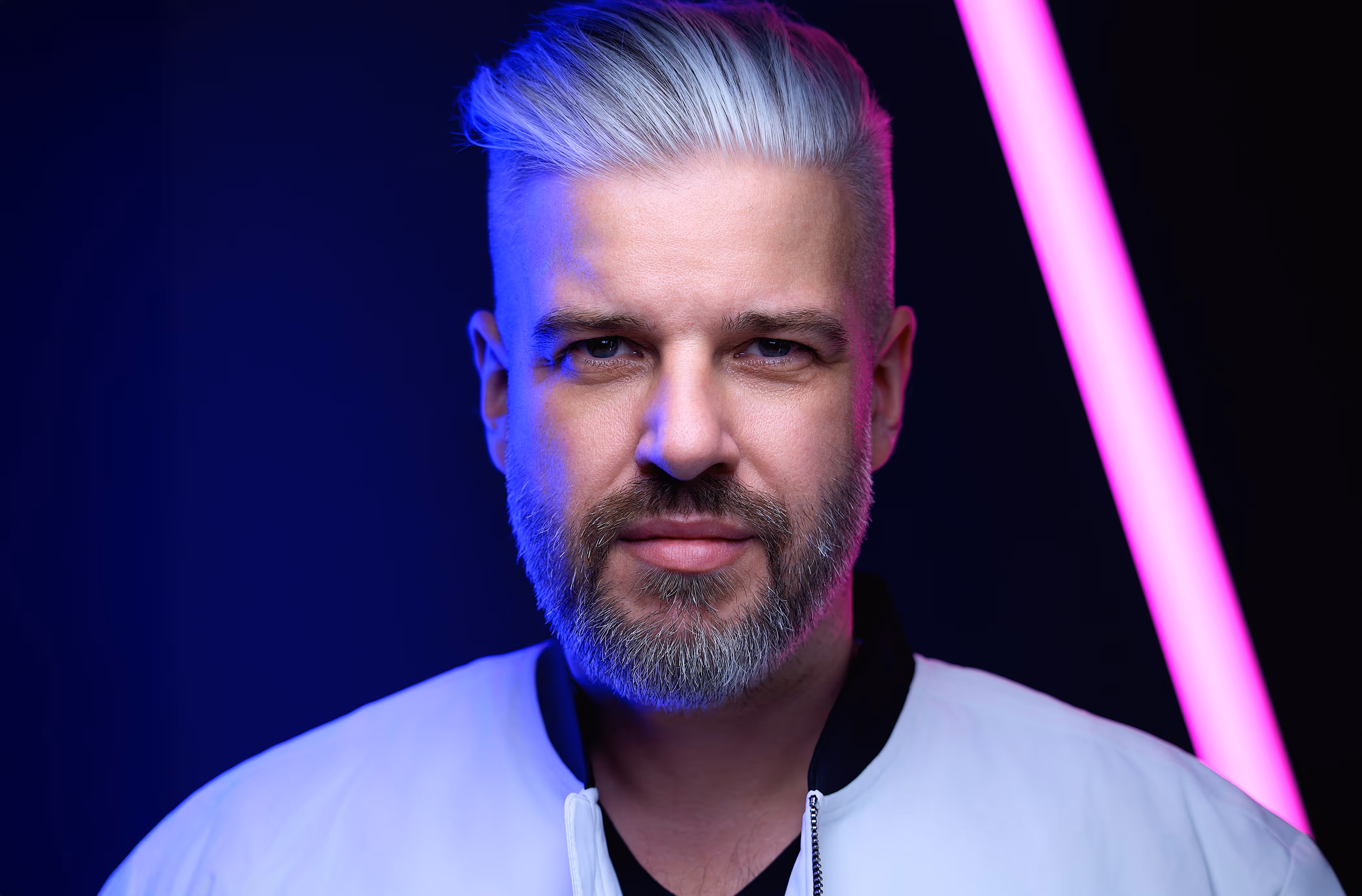 Headshot of Pete Fox in a white jacket and neon colors.