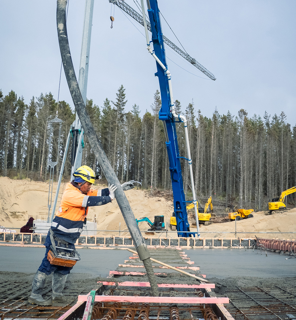 Concrete pumping team in Northland wearing safety gear and reviewing plans on site.
