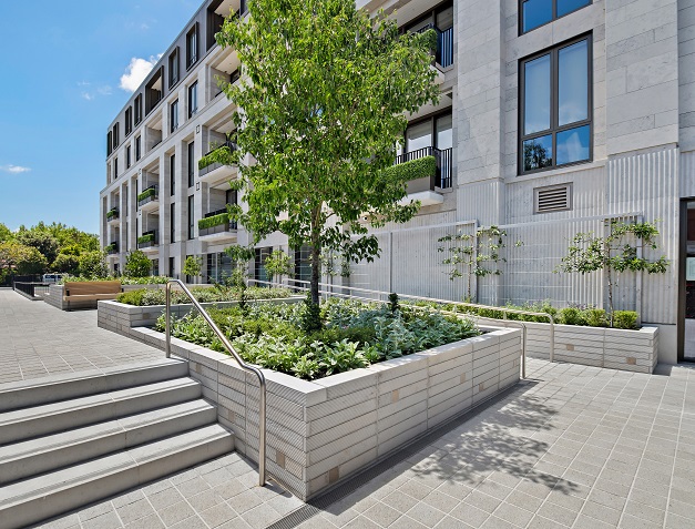 Landscaped courtyard at The Foundation featuring raised garden beds, stairs, and greenery against the apartment façade.