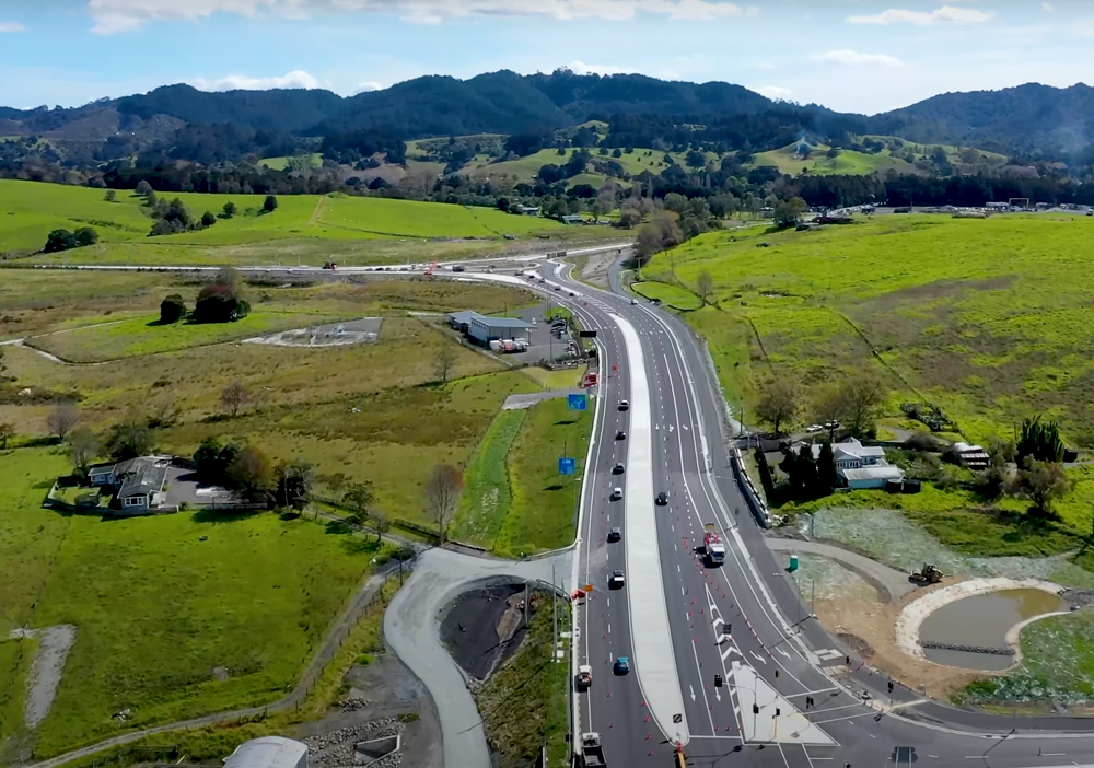 Aerial view of new multi-lane highway construction surrounded by green hills and farmland near Warkworth, part of the Ara Tūhono – Pūhoi to Warkworth motorway project in New Zealand.