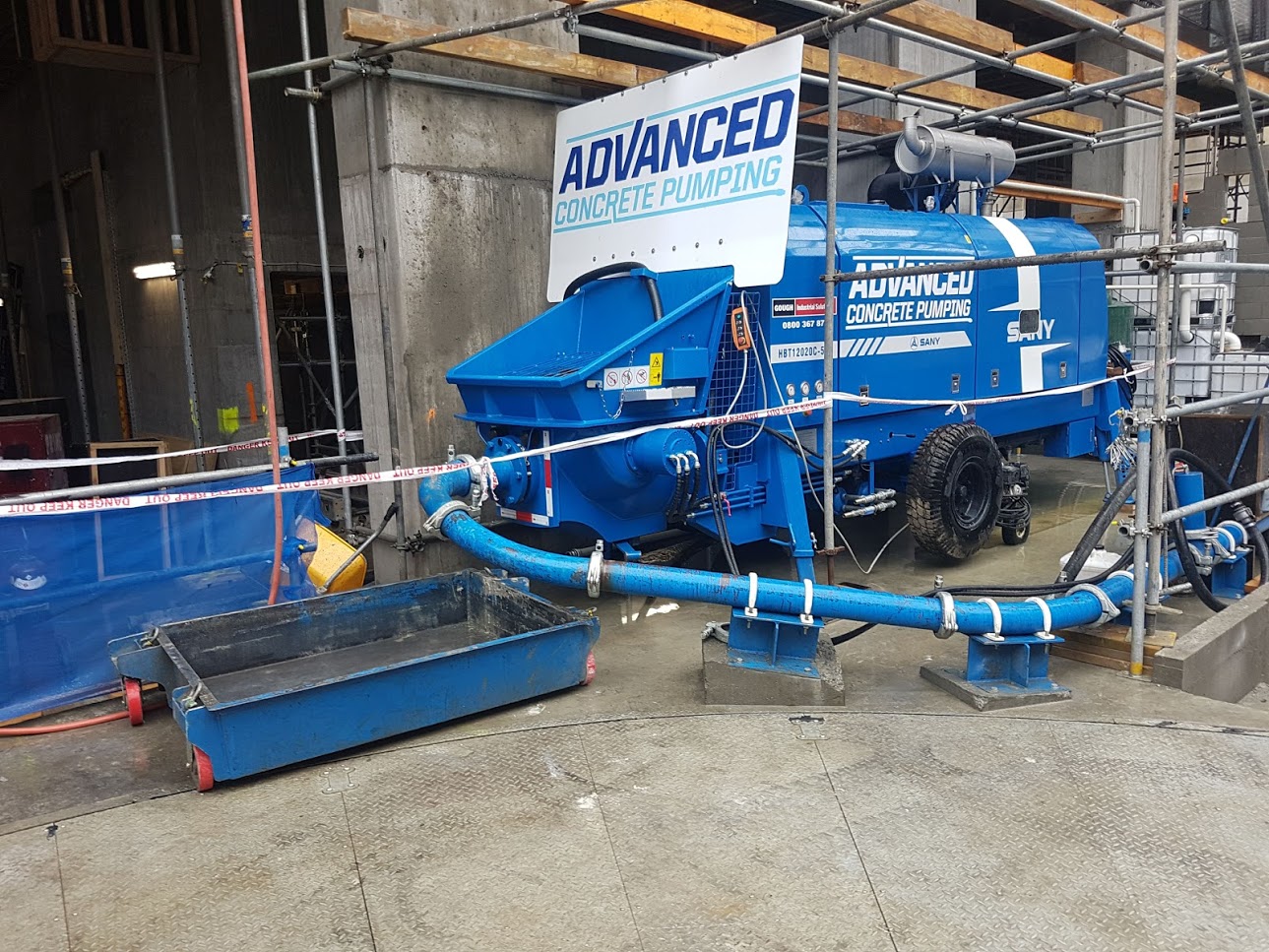Advanced Concrete Pumping stationary unit set up on a construction site with reinforced slab formwork and scaffolding during a commercial build.