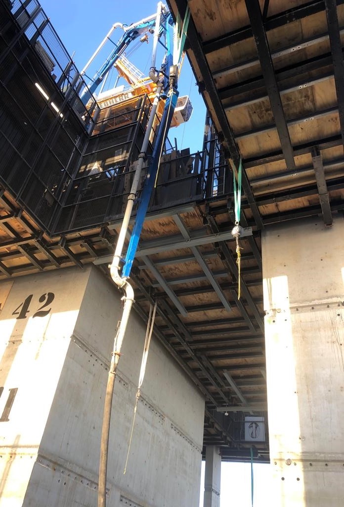 Concrete boom pumping through elevated formwork during multi-storey construction, showing height access and structural framework in progress