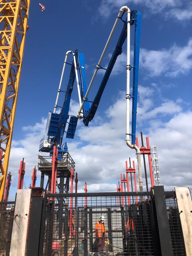 Advanced Concrete Pumping equipment positioned on upper levels of a high-rise build in Auckland, with boom arms extended and crew preparing for a concrete pour.