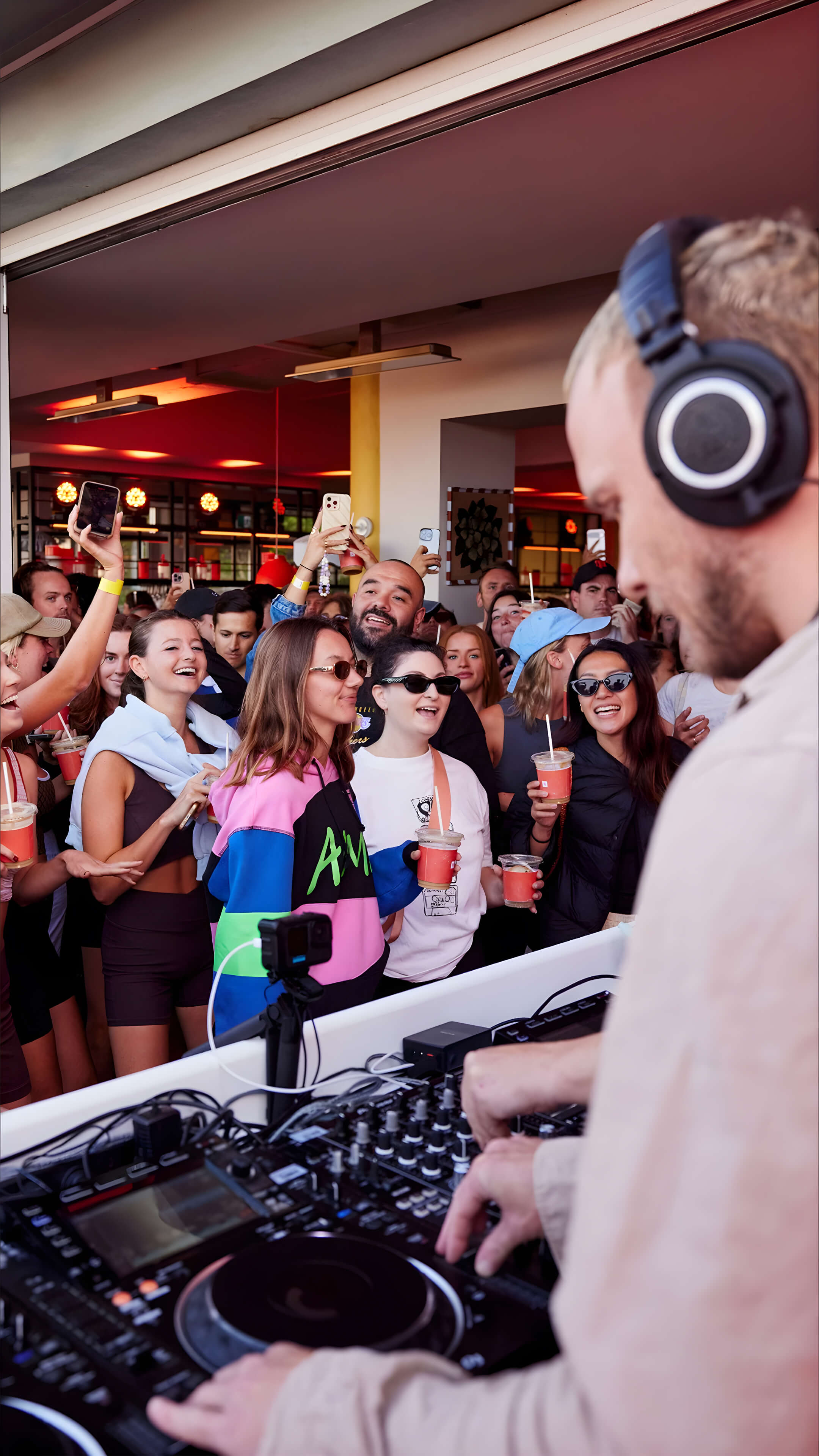 DJ performing at the Nespresso Happy Hour event in Bondi as a lively crowd dances, sings, and holds branded drinks in the front row.