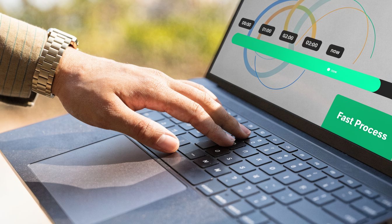 A close-up view of a person using a laptop to monitor a business process on screen.