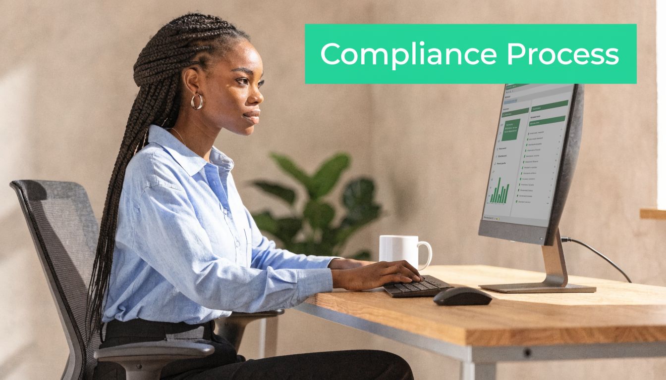 A professional woman working at a computer desk focusing on a digital compliance process interface.