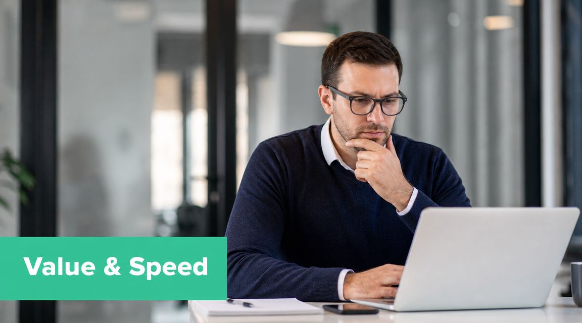 A professional man with glasses sitting at a desk and thinking while working on a laptop.