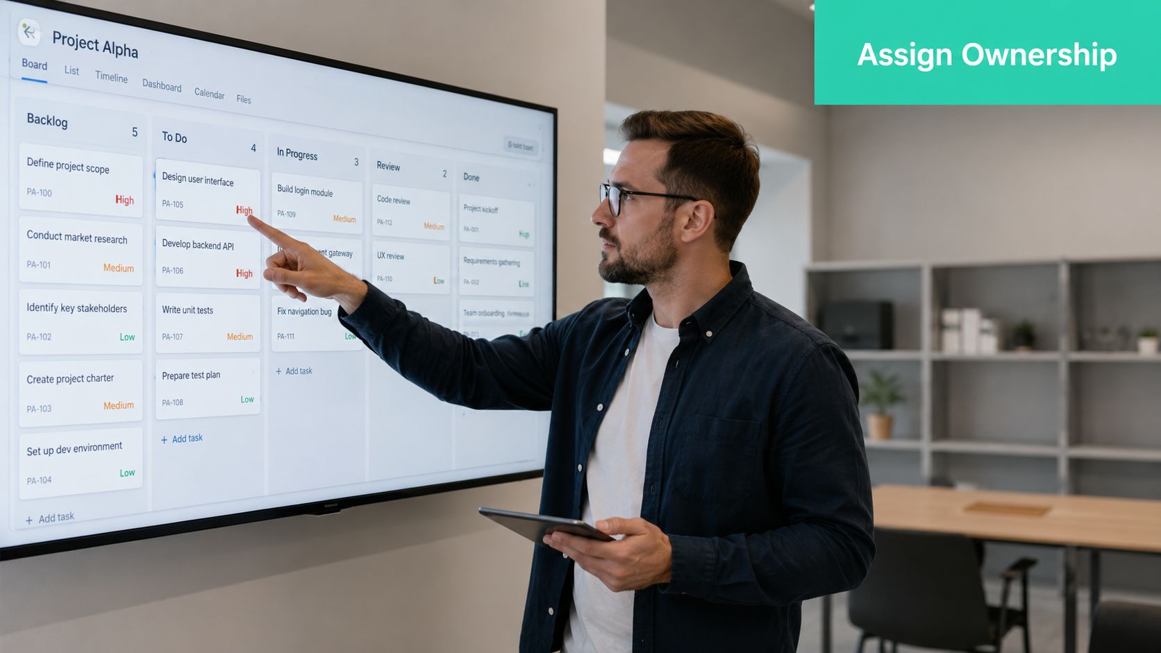 A professional man pointing at a digital project management board while holding a tablet in an office.