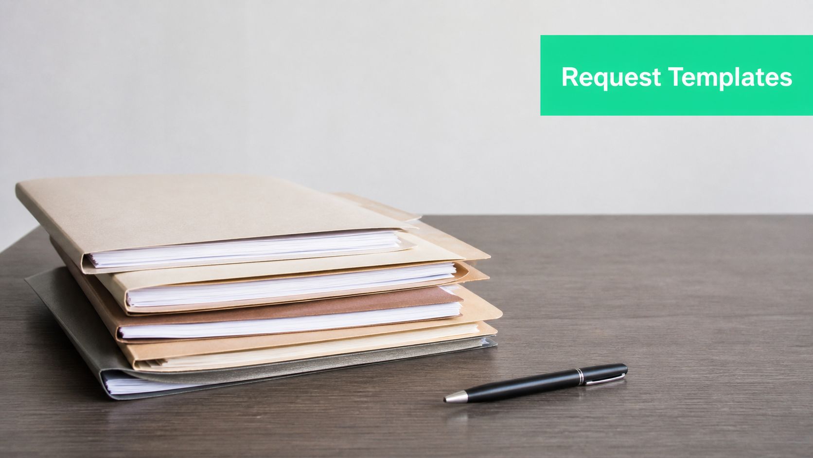 A stack of organized file folders and a black pen sitting on a wooden desk surface.
