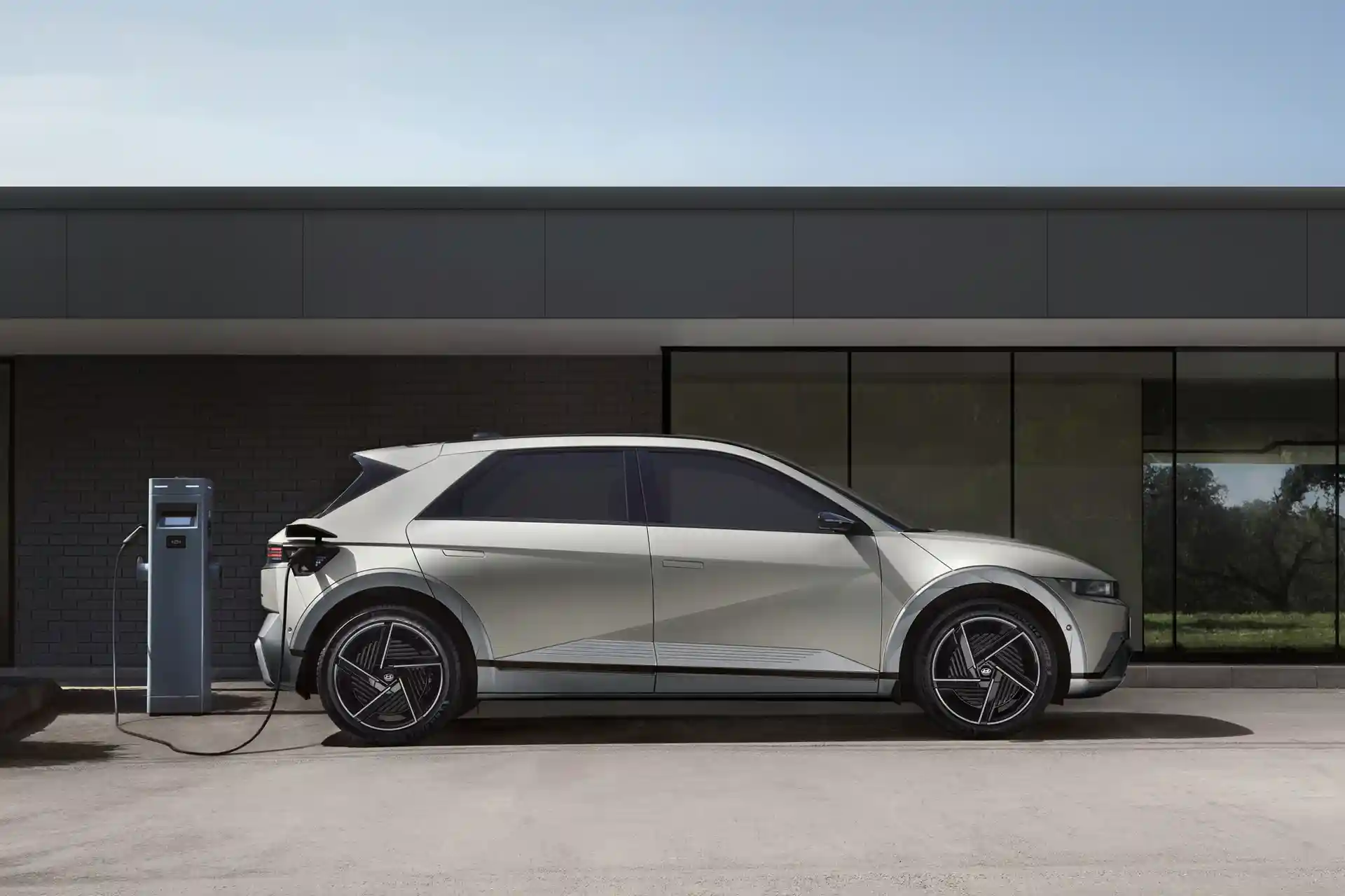 A new electric car being charged outside a modern home