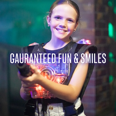 A smiling girl holds a lasertag phaser