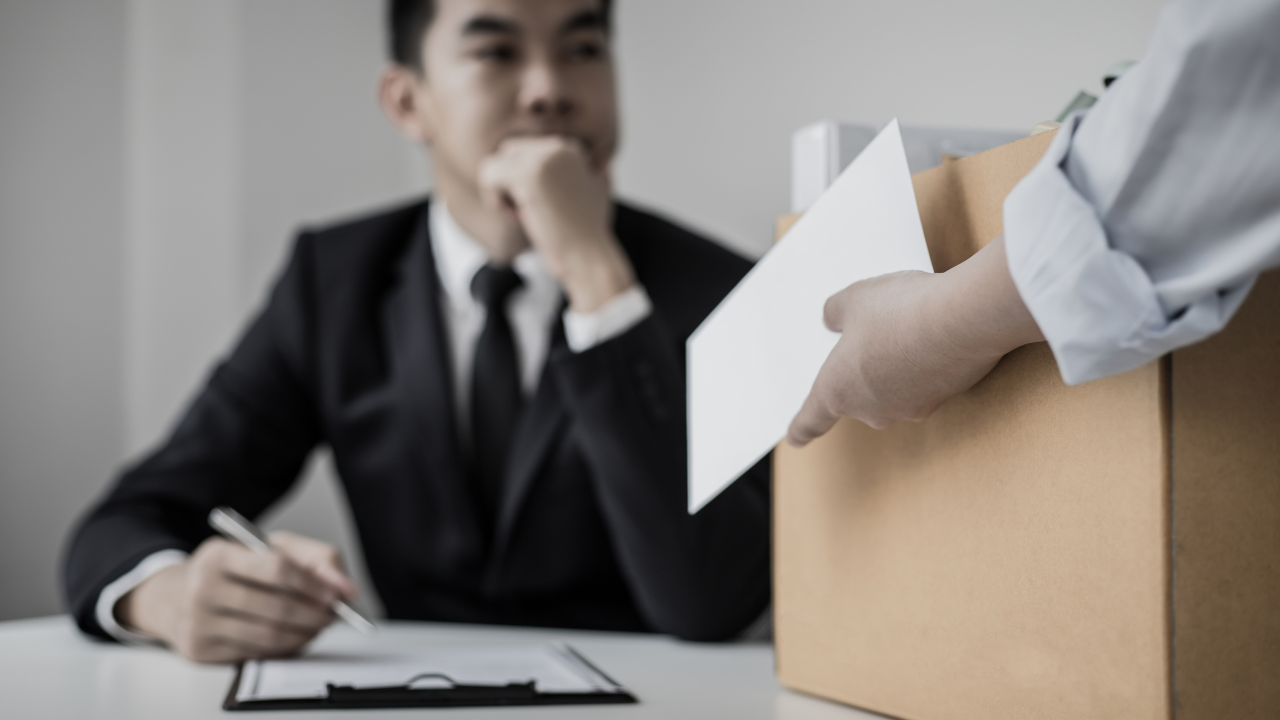 a man in suit infront of a collegue holding a box