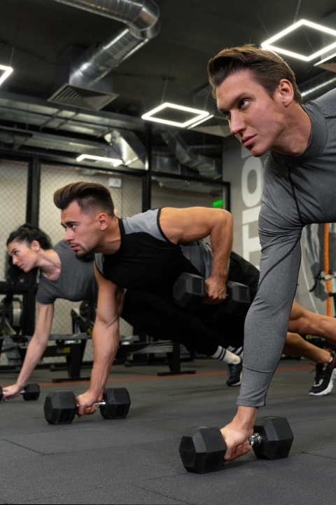 Three men performing push-ups in a gym at CrossFit Vinita LLC, located in Vinita, OK.