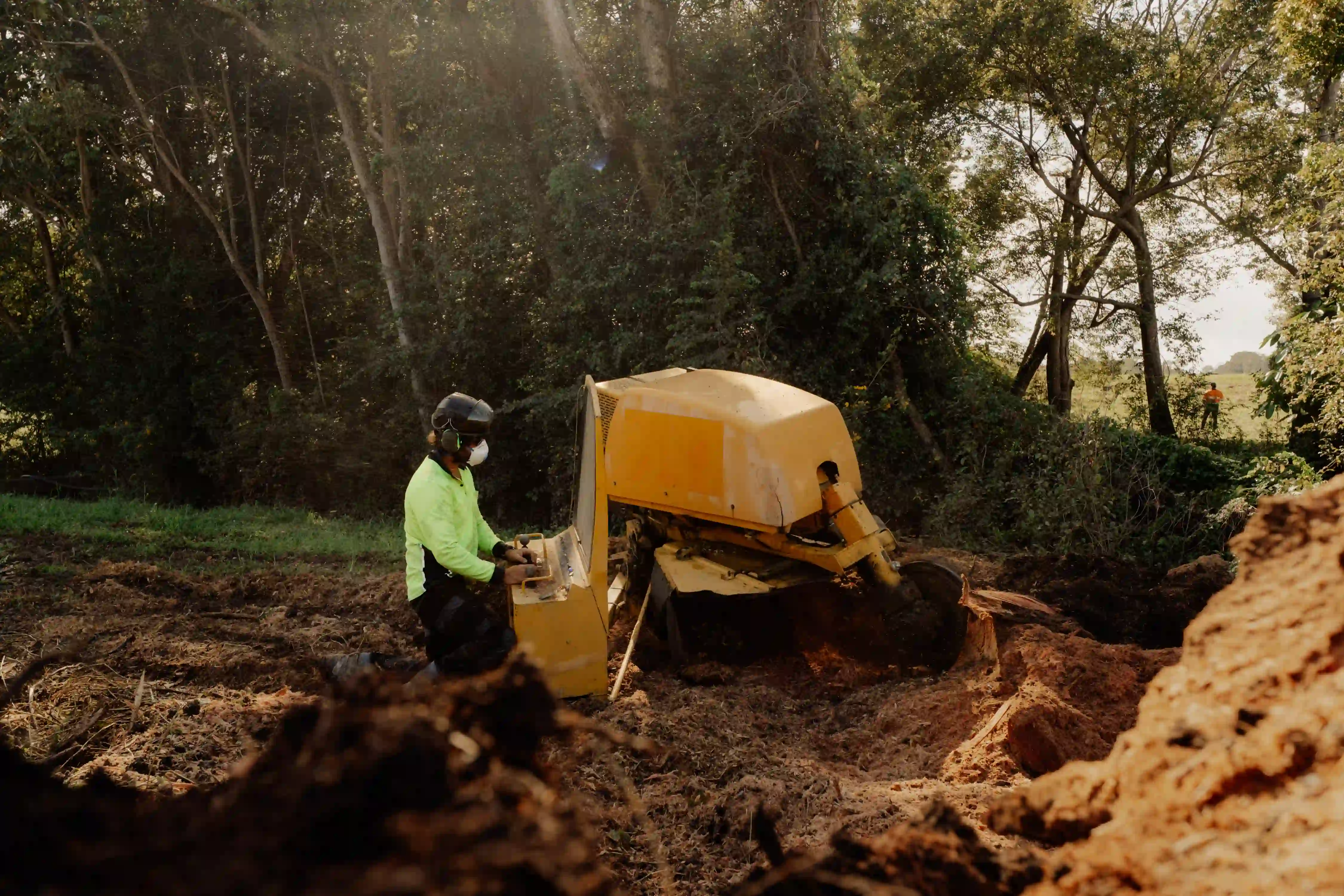 A man standing next to a yellow bulldozer.