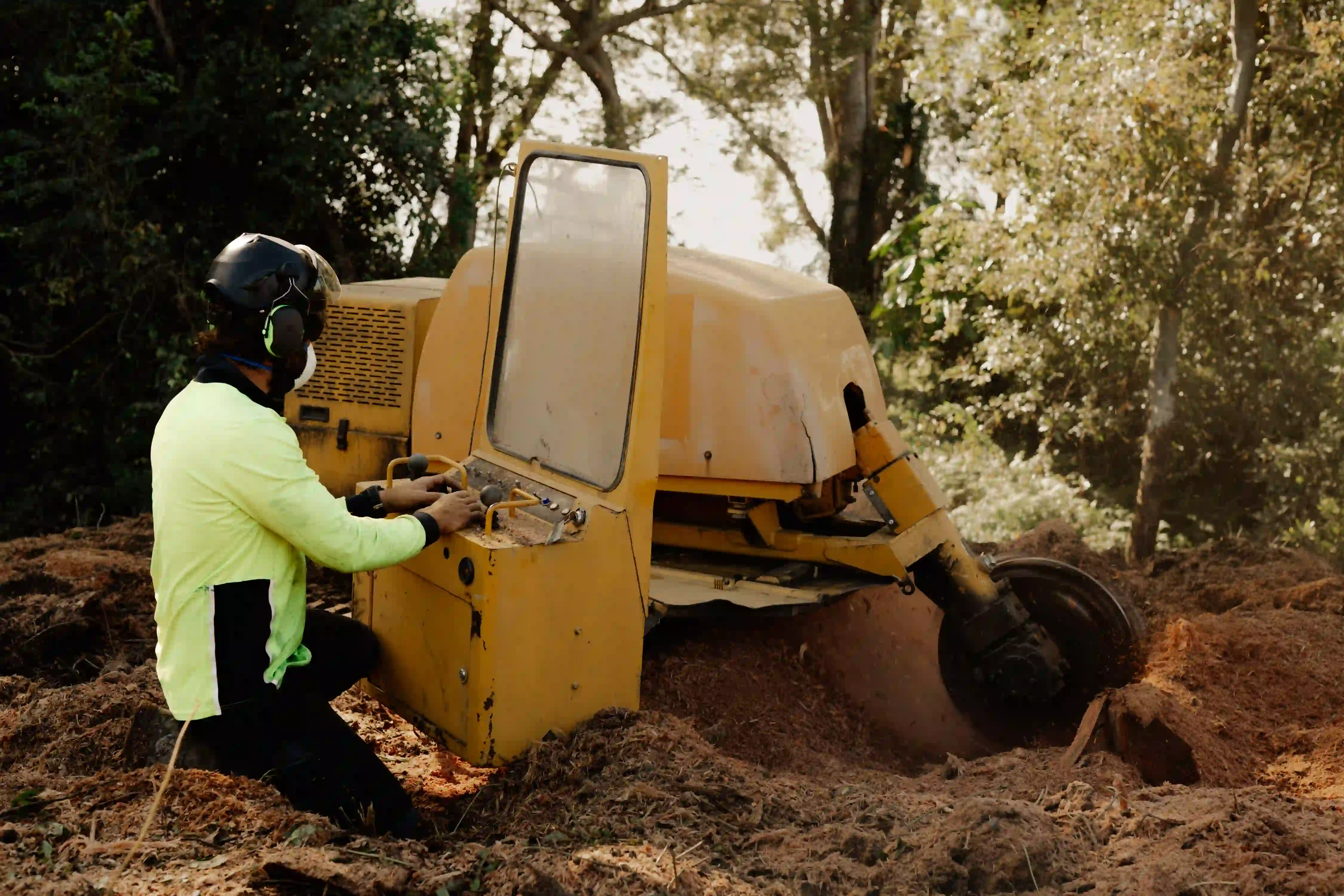 A man in a yellow jacket is digging dirt.