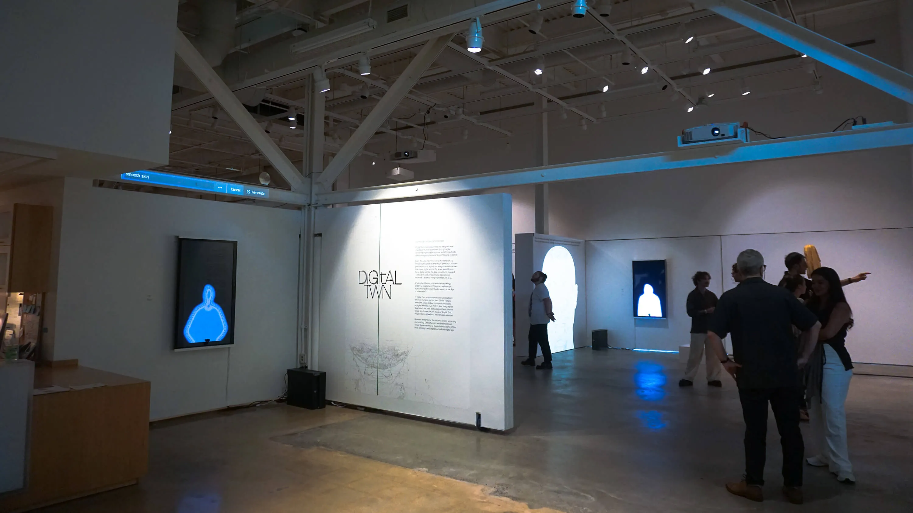 Gallery space with illuminated text reading 'Digital Twin' on a central wall, digital art projections of blue and white human silhouettes, and visitors observing and interacting.