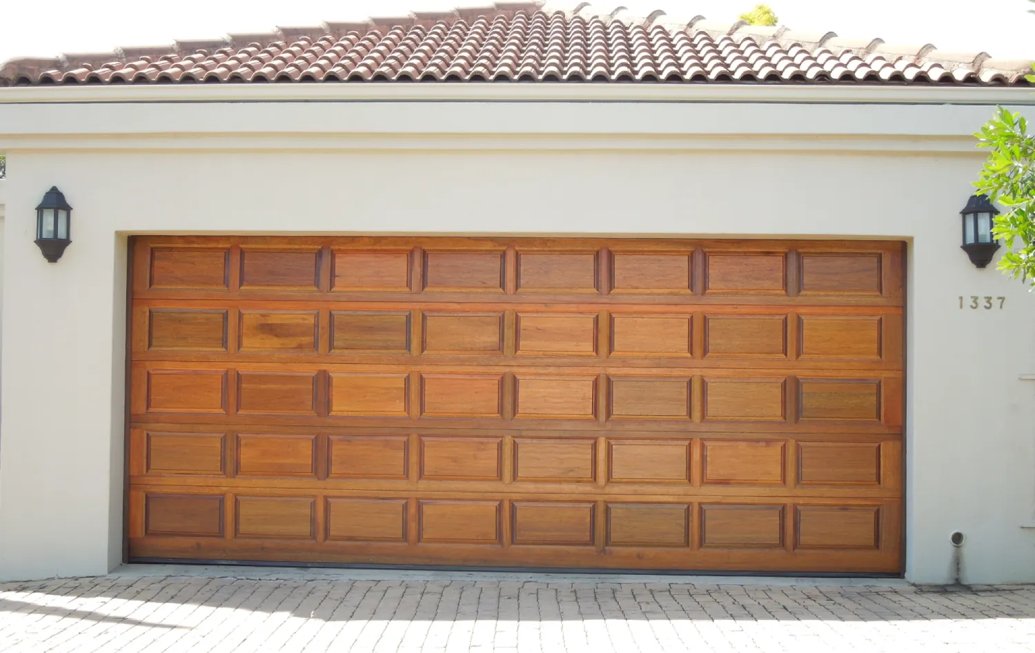 Large wooden garage door with 40 rectangular panels set in a white stucco wall under a tiled roof.