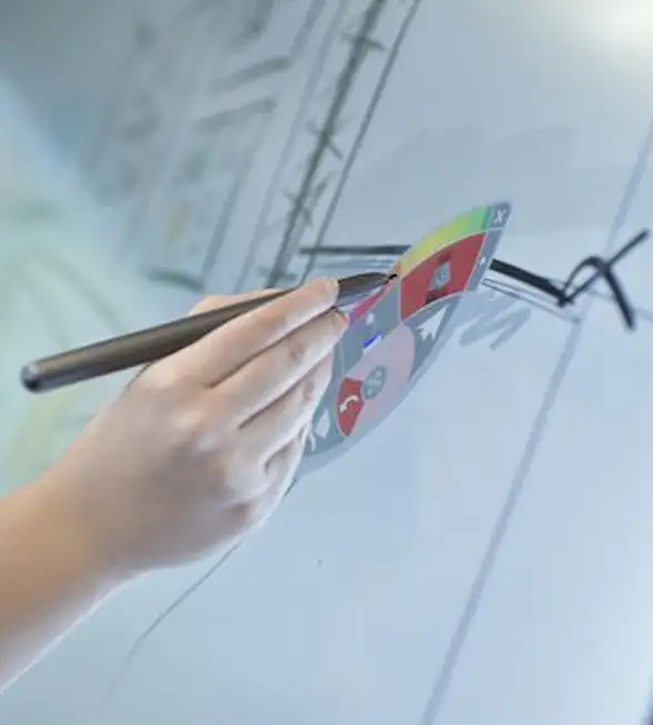 Main tenant un stylo et dessinant sur un tableau blanc avec des éléments graphiques colorés.