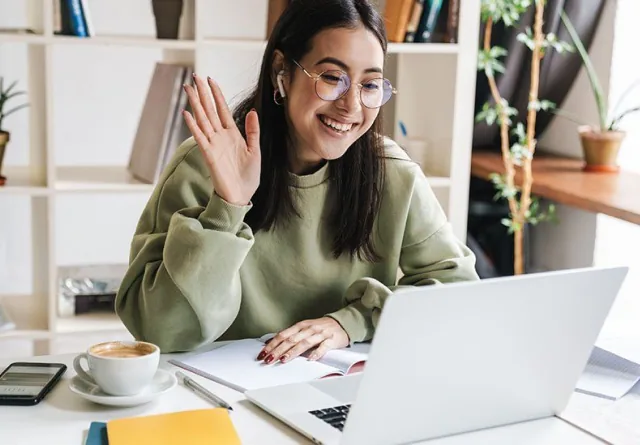 Woman waving during a video call about outsourced email marketing.
