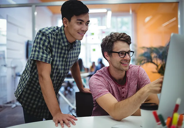 Two colleagues smiling while reviewing a digital marketing dashboard together.