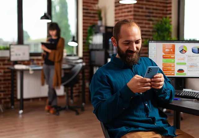 Man smiling while checking social media analytics on his phone.