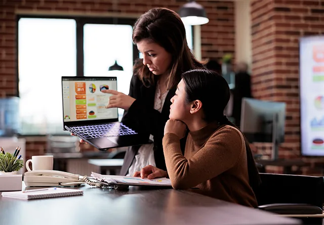 Two colleagues discussing SEO analytics on a laptop screen.