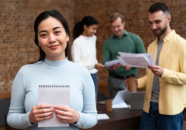 Woman holding a notepad while weighing outsourcing pros and cons in the office.