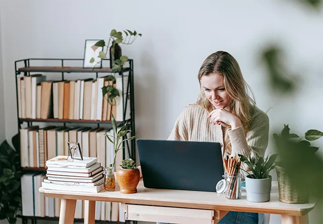 Woman smiling at her laptop while researching nearshore staffing agencies.