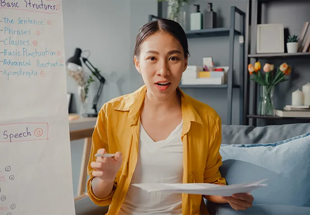 Woman presenting a lesson on marketing outsourcing in front of a whiteboard.