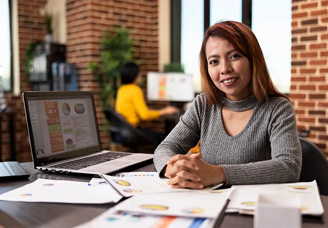 Woman smiling at her desk while comparing marketing talent hiring platforms.