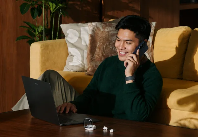 Man smiling on the phone while discussing social media management costs.