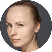 Портрет женщины с светлой кожей и собранными назад волосами на темном фоне.