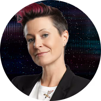 Smiling man with glasses, a beard, and a blue shirt against a dark abstract background.