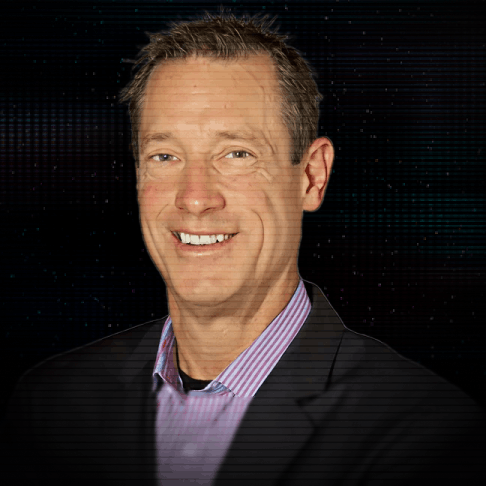 Smiling woman with neon green bob haircut and bangs wearing a black hat and light-colored blazer.