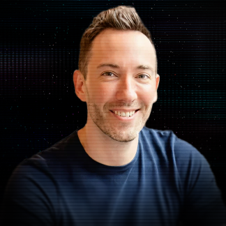 Smiling middle-aged man with short brown hair wearing a dark blazer and light purple striped shirt against a black background.