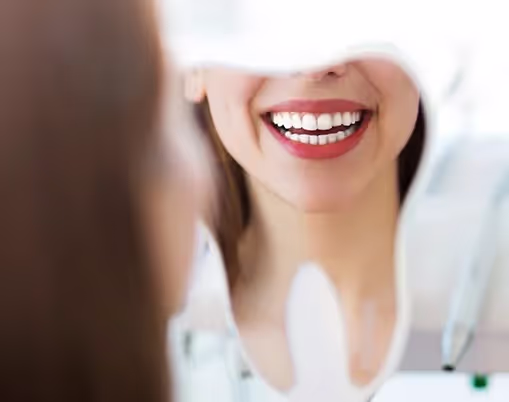 A woman is smiling and holding a toothbrush.