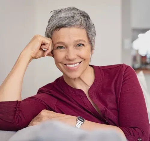 A woman sitting on a couch with a watch on her wrist.