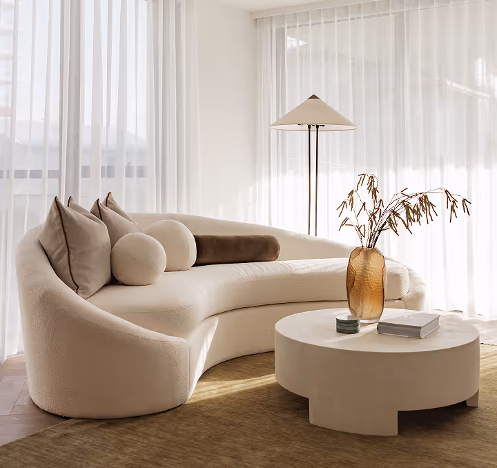 Modern dining room with a wooden table, eight beige cushioned chairs, and a contemporary pendant light above.