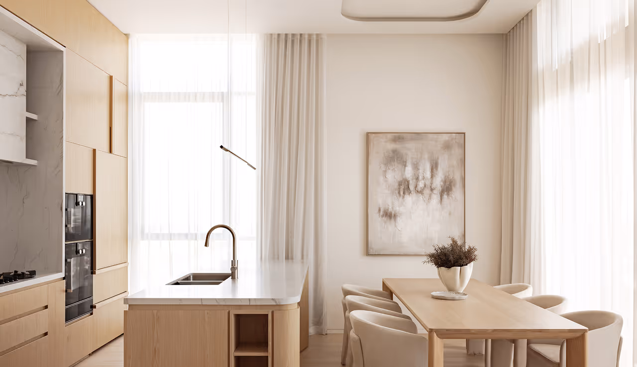 Modern kitchen and dining area with light wood furnishings, marble countertops, and white sheer curtains.