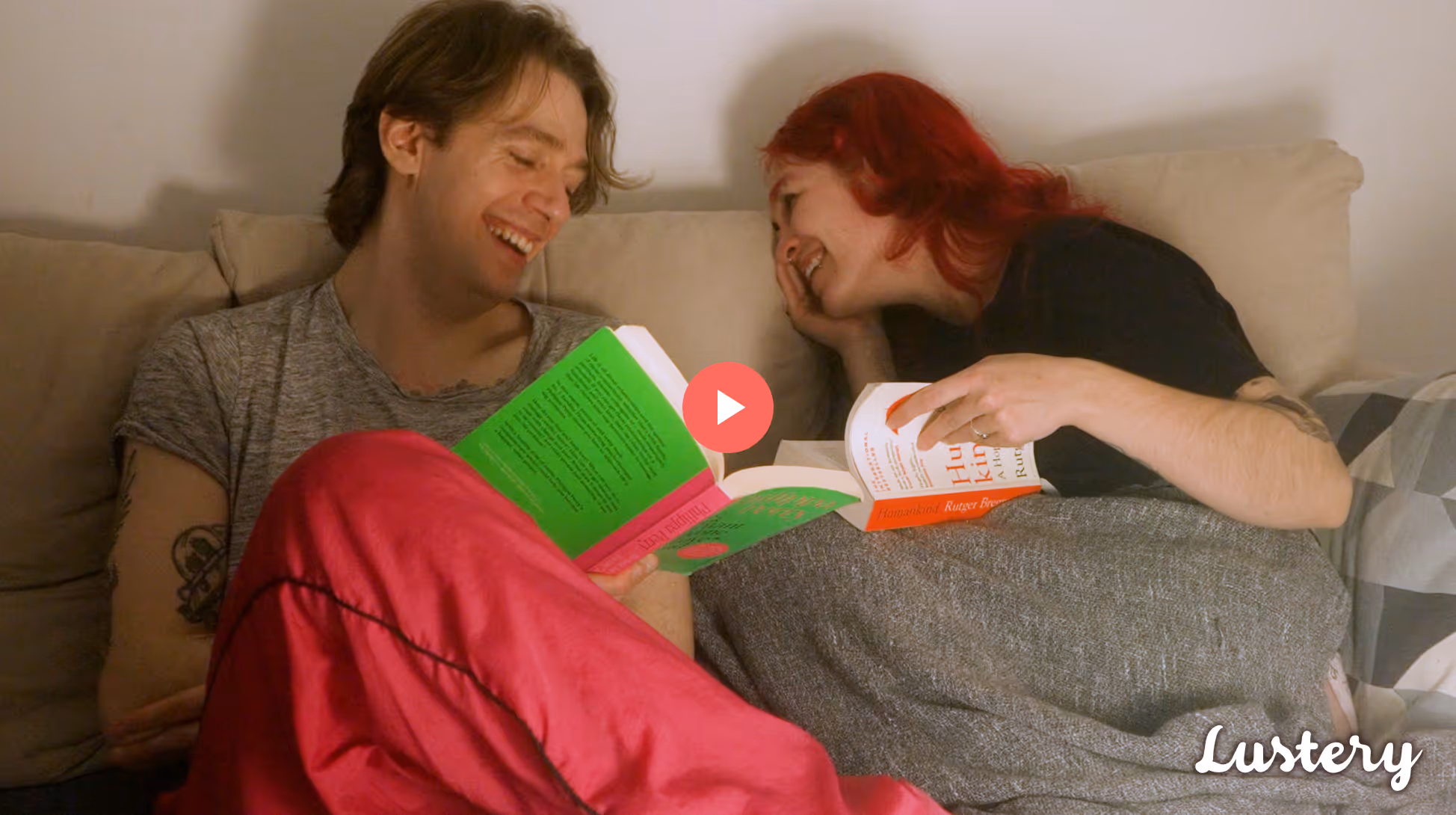 Real life couple Cedric and Sofi sit on a tan couch laughing and reading together.