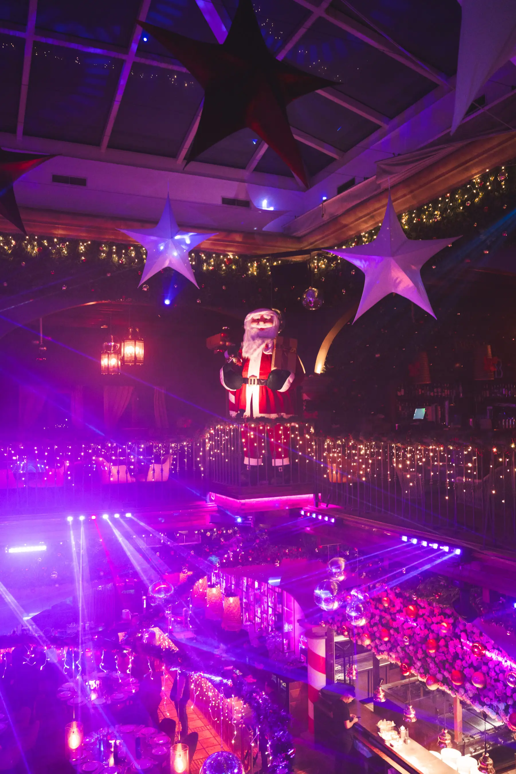 Santa-themed performer on stage at Tabana’s Dirty Santa event with festive lights and disco balls.