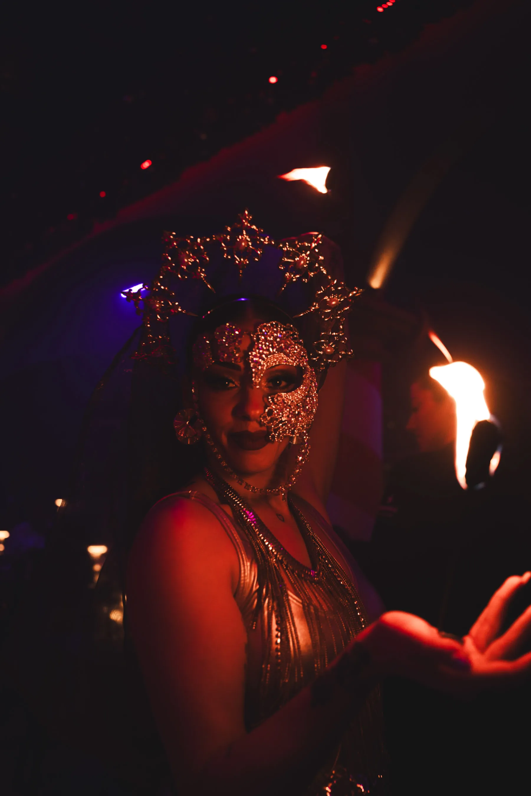 Performer in gold mask and festive costume entertaining guests with fire during Dirty Santa.